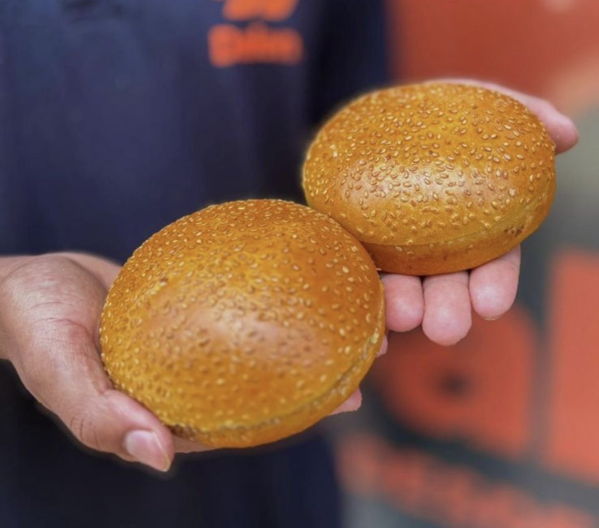 Colaboradora da Dalen segurando dois pães de hambúrguer